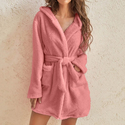 a woman wearing a pink robe standing next to a wall